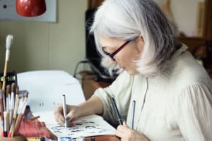 Una mujer usa papel y plumas para crear arte y mantenerse ocupada.